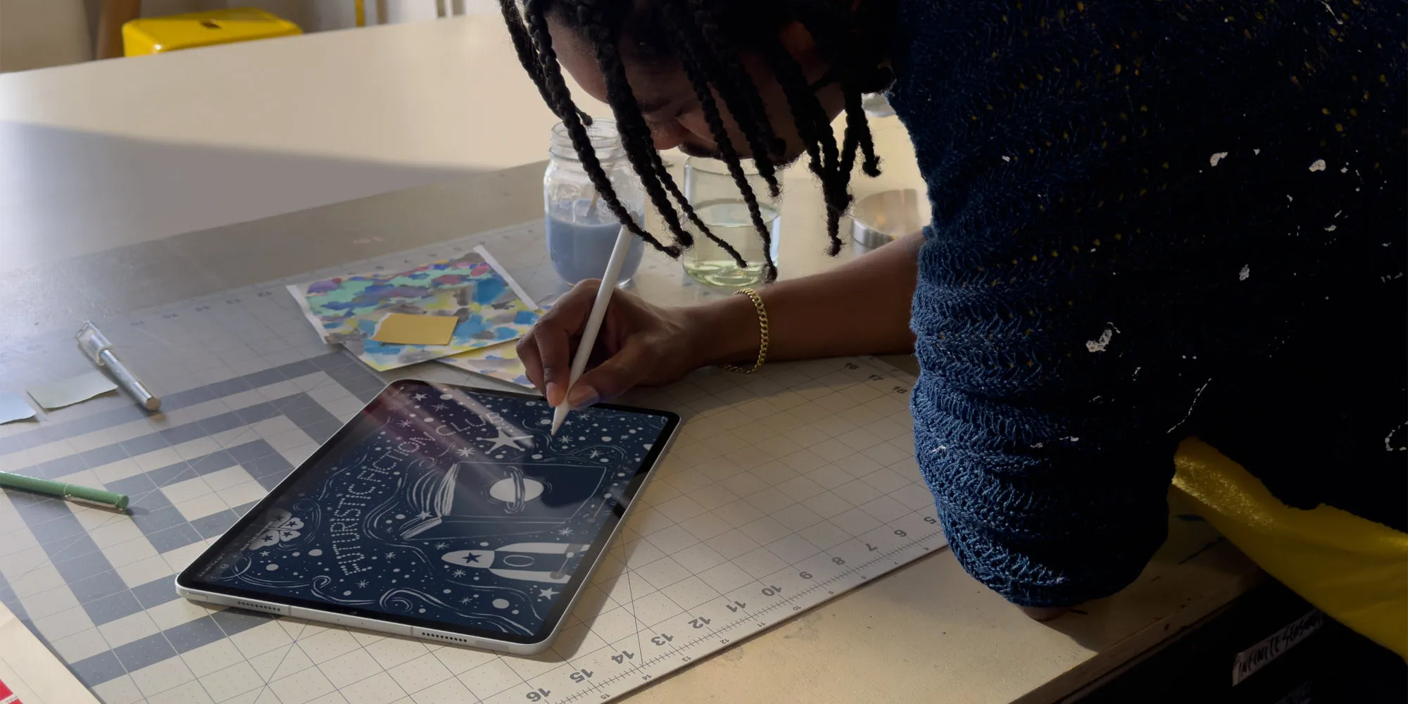 An individual drawing digitally on a tablet using a stylus while working at a desk.